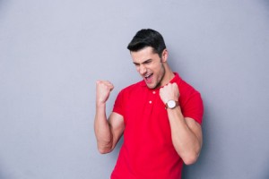 Casual man celebrating success over gray background